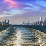 Cruise wash foam in Hudson river and Panoramic view of Statue of Liberty and Manhattan and Jersey city  in New York City, NY, USA