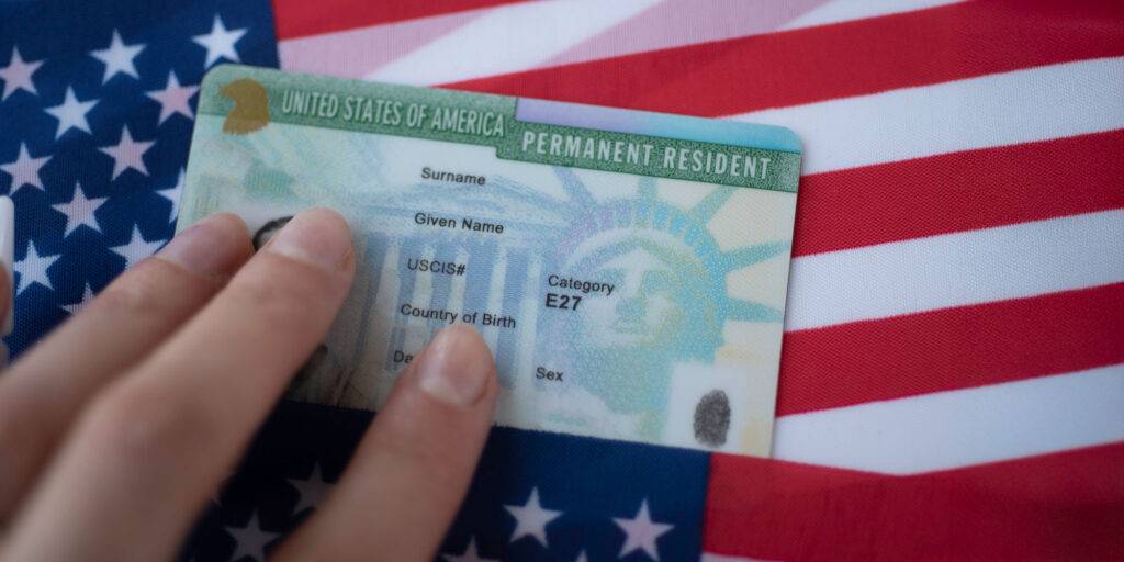 USA permanent residency green card on American flags